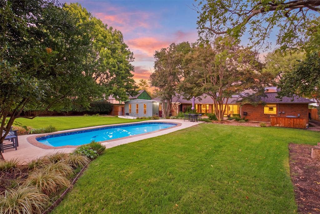Golden hour at the pool, with the home and studio glowing beyond the lawn.