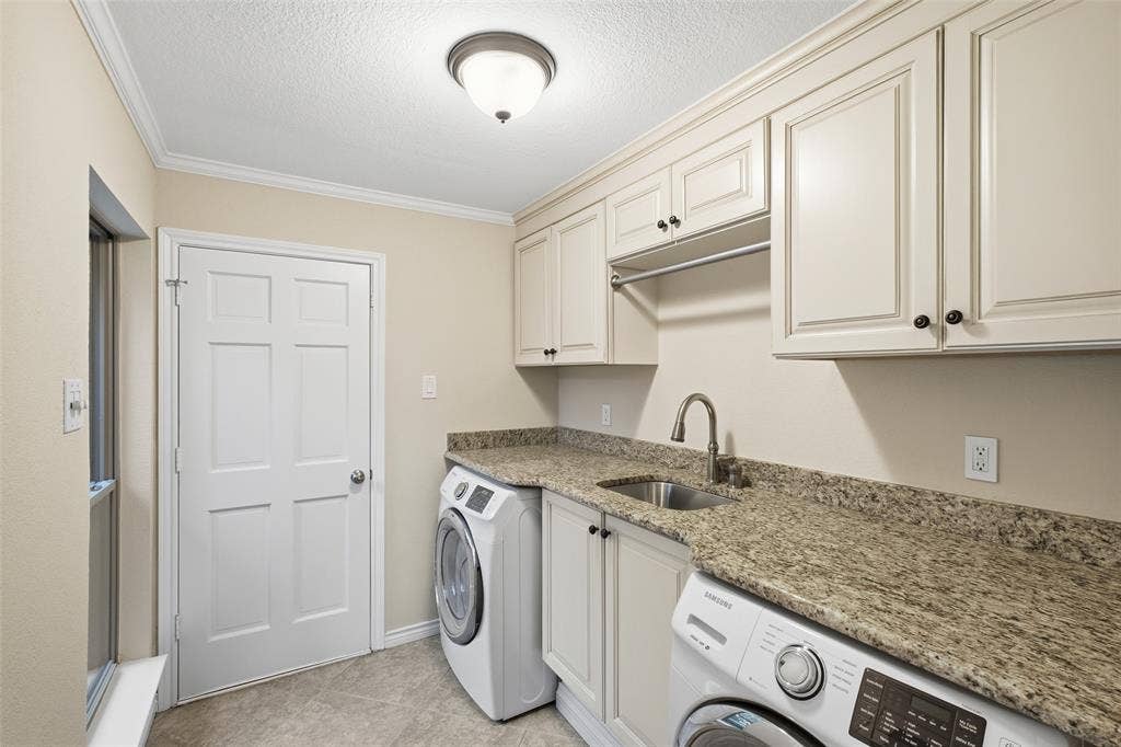 Laundry day made easy: granite counter, sink, raised-panel cabinetry and a hanging rod.