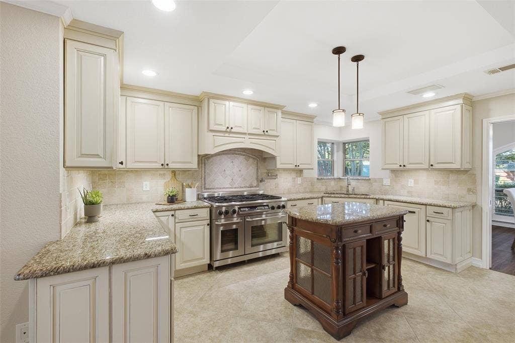 Chef's kitchen with granite counters, six-burner range with double ovens, pot filler and tile backsplash.