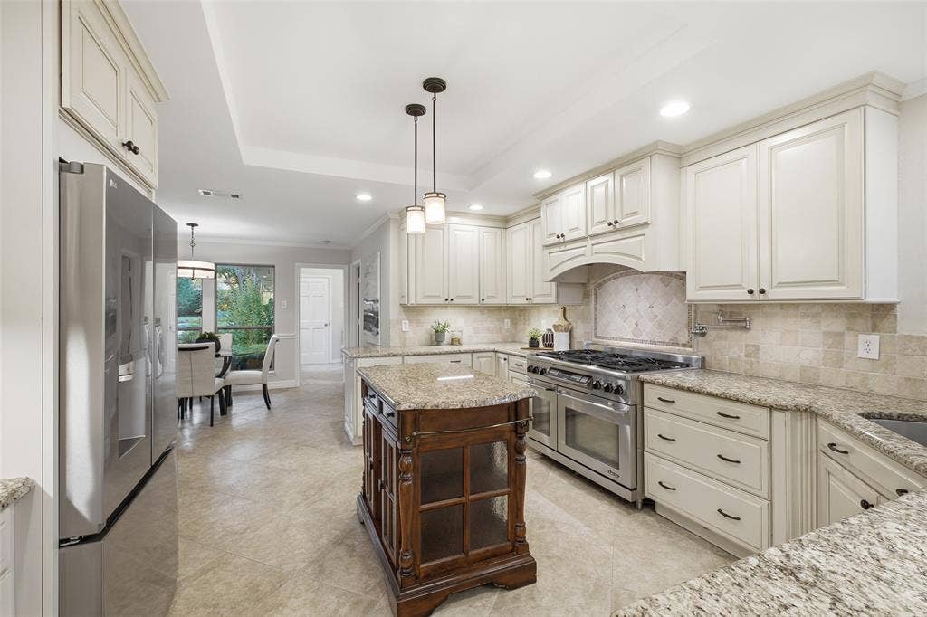 Smart kitchen storage: raised-panel cabinetry with toe-kick drawers, pendant lighting and a tray ceiling.