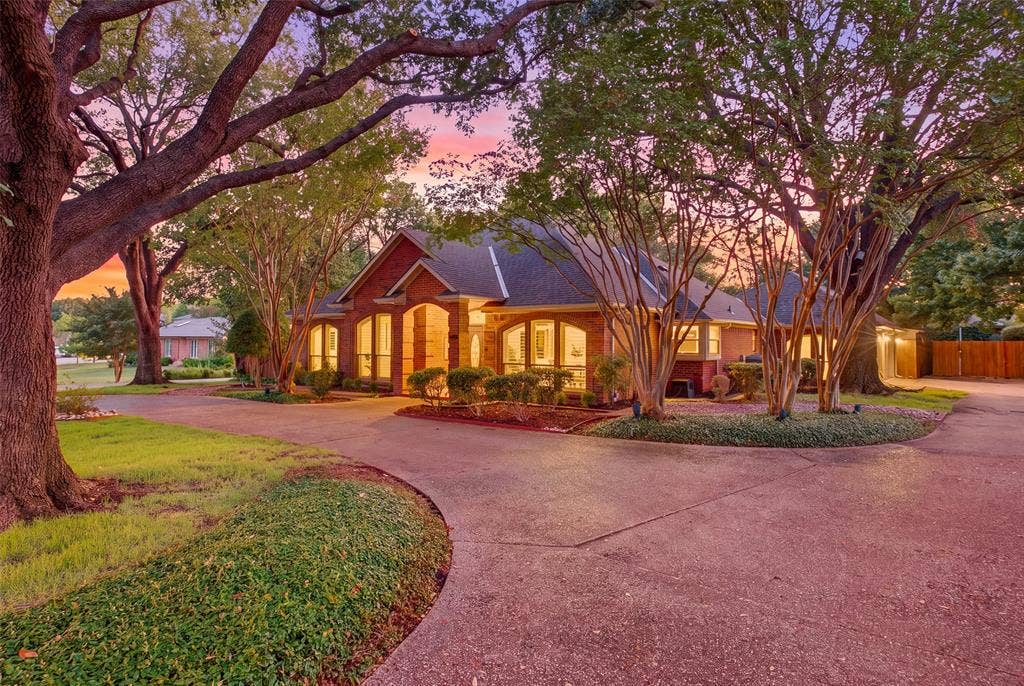 Curb appeal that sets the tone: lush landscaping, circular drive and a warm glow from every window.