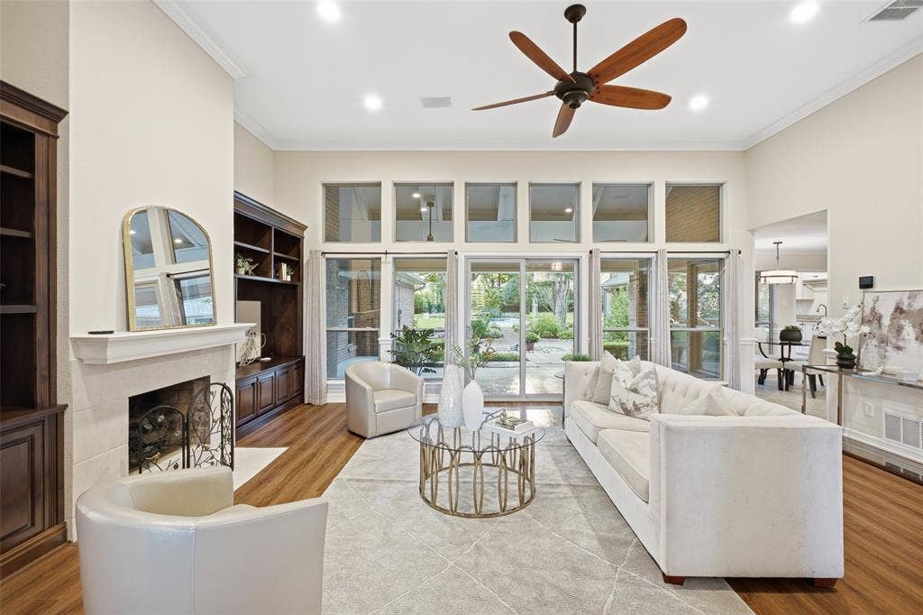 A wall of windows with transoms floods the living room with natural light and frames courtyard and pool views.