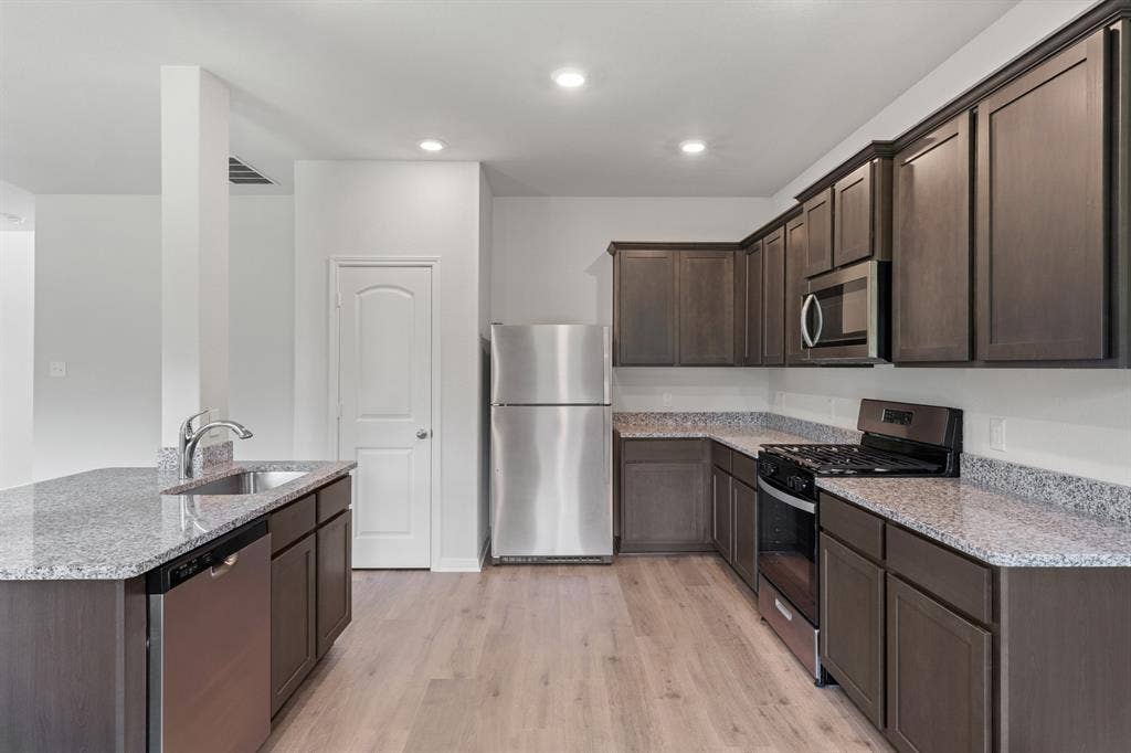 1534 William Wallace Street, Crandall, TX 75114 Kitchen featuring stainless steel appliances, dark brown cabinetry, light stone counters, light wood-type flooring, and recessed lighting