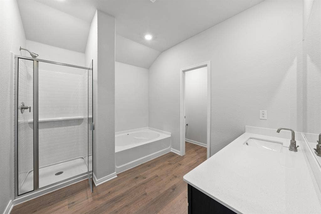 1439 Reiner Drive, Crandall, TX 75114 Bathroom with vanity, wood-type flooring, plus walk in shower, and vaulted ceiling
