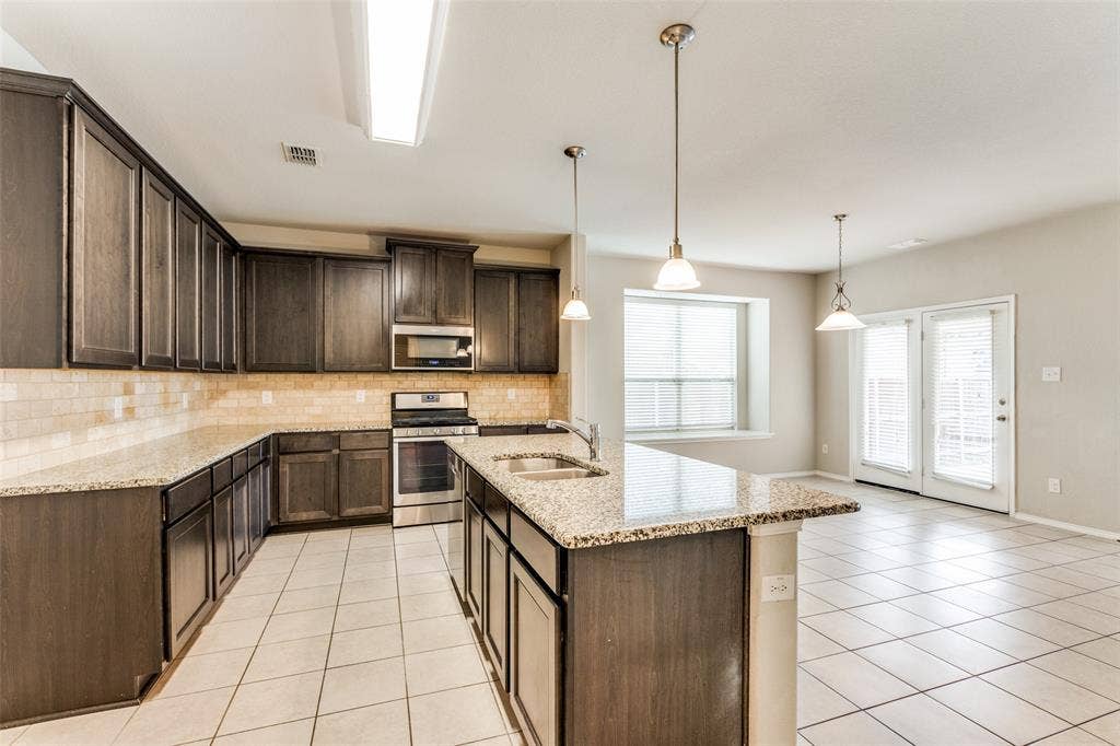 Kitchen featuring extensive dark-finish cabinetry, granite countertops, stainless steel appliances, and a tile backsplash