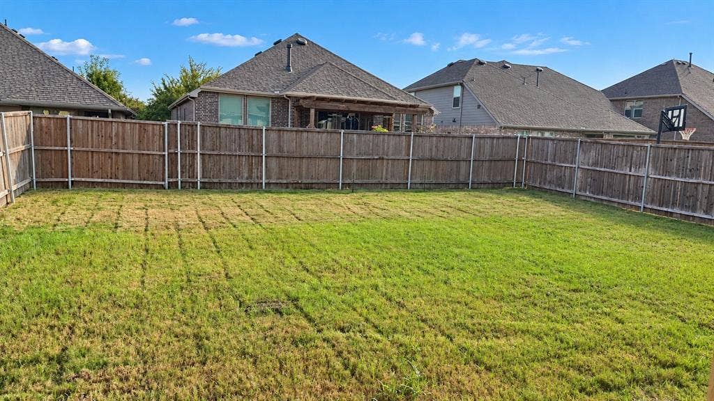 Expansive backyard featuring a wood fence perimeter and a manicured lawn