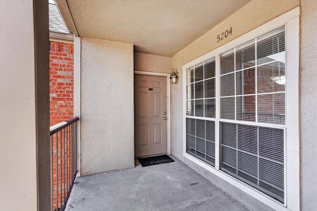 12660 Hillcrest Road, #5204, Dallas, TX 75230 Covered entryway featuring a metal railing, sconce lighting, and large window with grid pattern