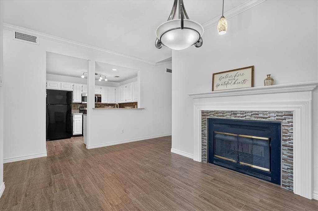12660 Hillcrest Road, #5204, Dallas, TX 75230 Wood-finish flooring, white walls, and a fireplace with a tile surround and white mantel