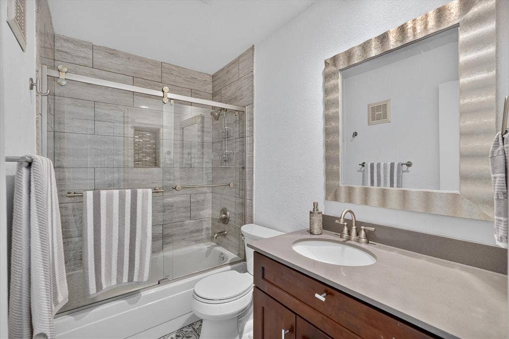 12660 Hillcrest Road, #5204, Dallas, TX 75230 Bathroom featuring a tub/shower combination with tile surround, glass sliding door, and a built-in shower niche