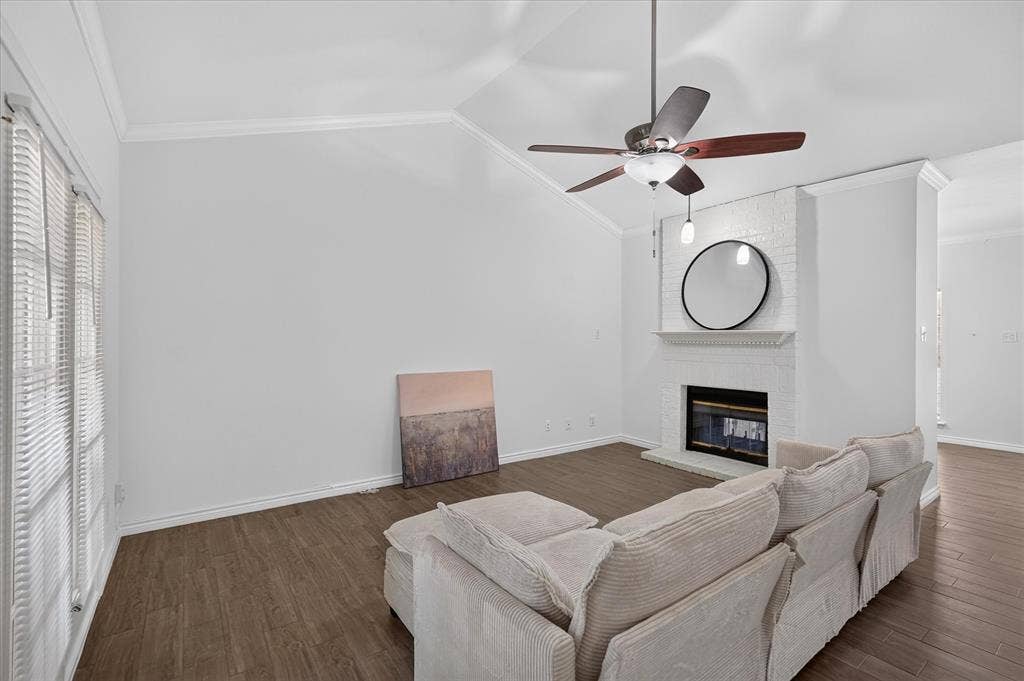 12660 Hillcrest Road, #5204, Dallas, TX 75230 Vaulted ceiling with a ceiling fan, white painted brick fireplace with hearth, and wood-finish flooring
