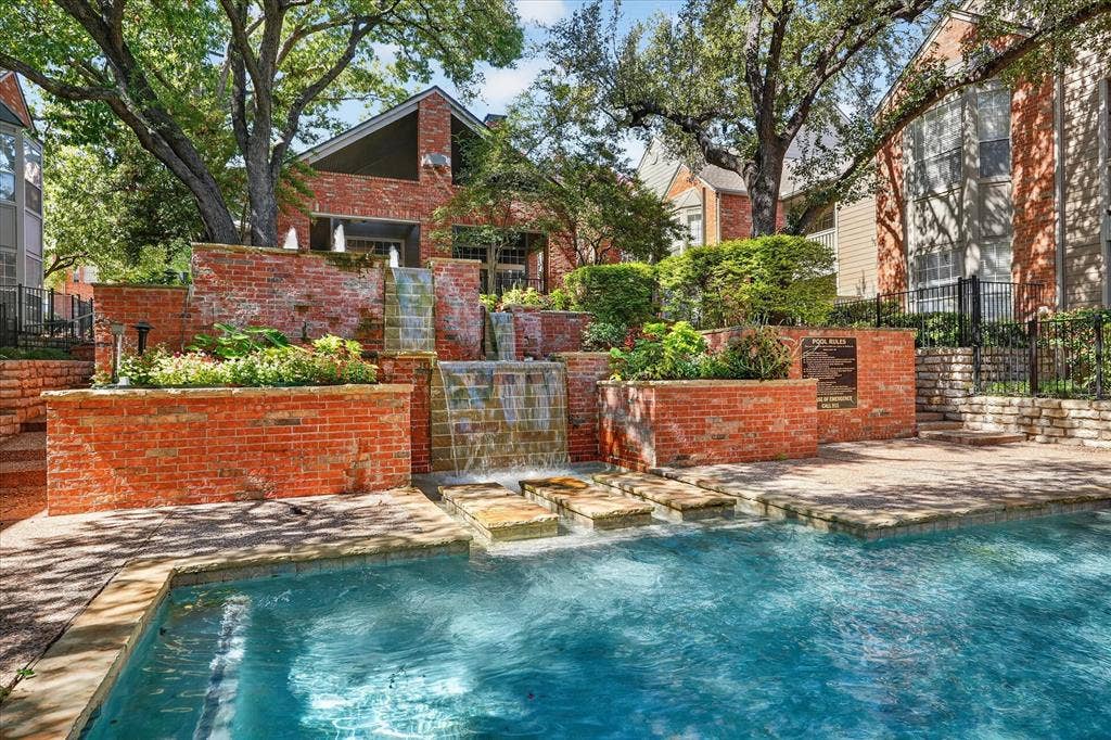 12660 Hillcrest Road, #5204, Dallas, TX 75230 Outdoor swimming pool with stone coping and a multi-tiered brick water feature with integrated planters