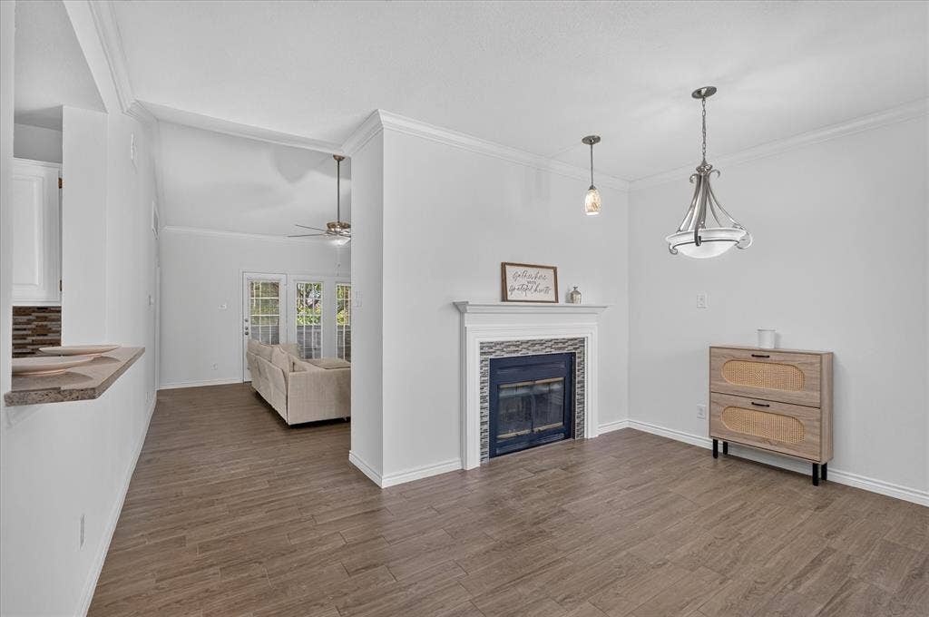 12660 Hillcrest Road, #5204, Dallas, TX 75230 Wood-finish flooring throughout, a fireplace with a tiled surround and mantel, and crown molding