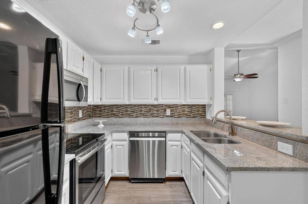 12660 Hillcrest Road, #5204, Dallas, TX 75230 Kitchen featuring white cabinetry, stone countertops, stainless steel appliances, a tiled backsplash, and wood-finish flooring