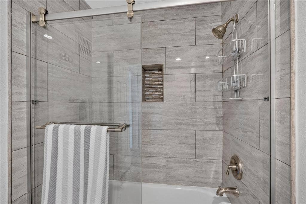 12660 Hillcrest Road, #5204, Dallas, TX 75230 Bathtub with light gray subway tile surround and integrated tiled niche