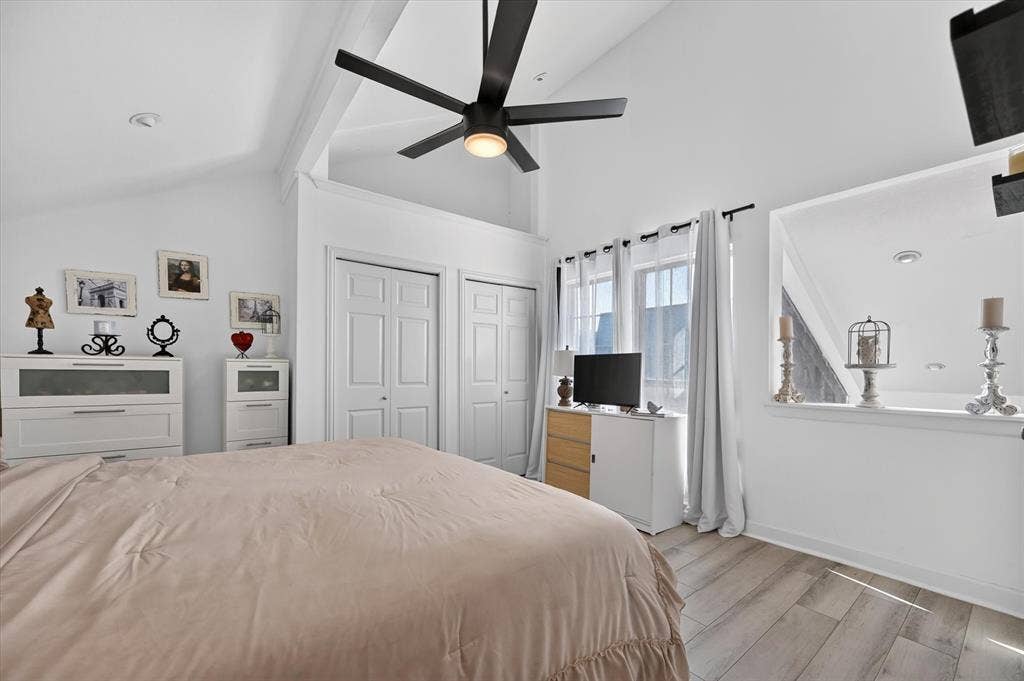 Vaulted ceiling with exposed beams, wood-finish flooring, and white trim