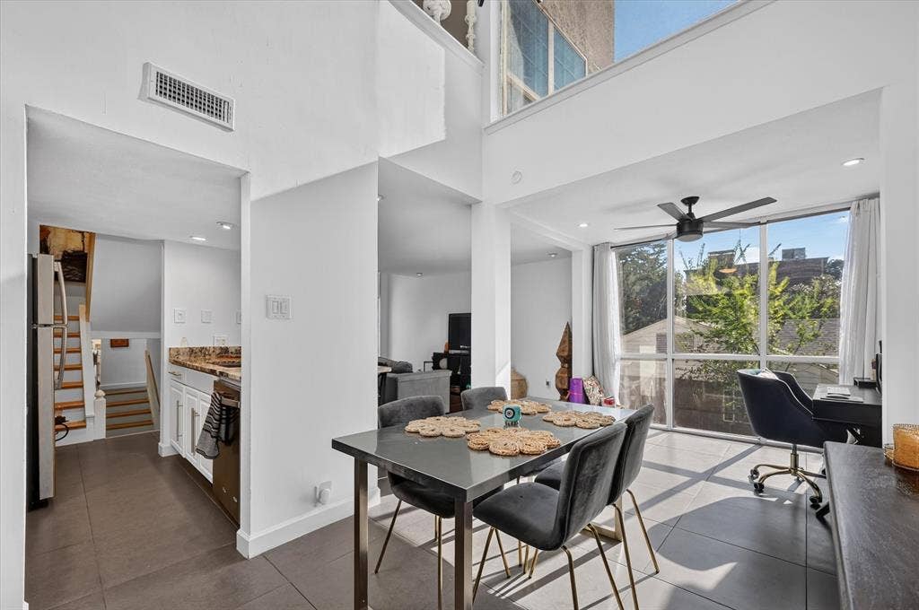 Two-story living space with high ceilings and large windows, featuring a modern ceiling fan and recessed lighting