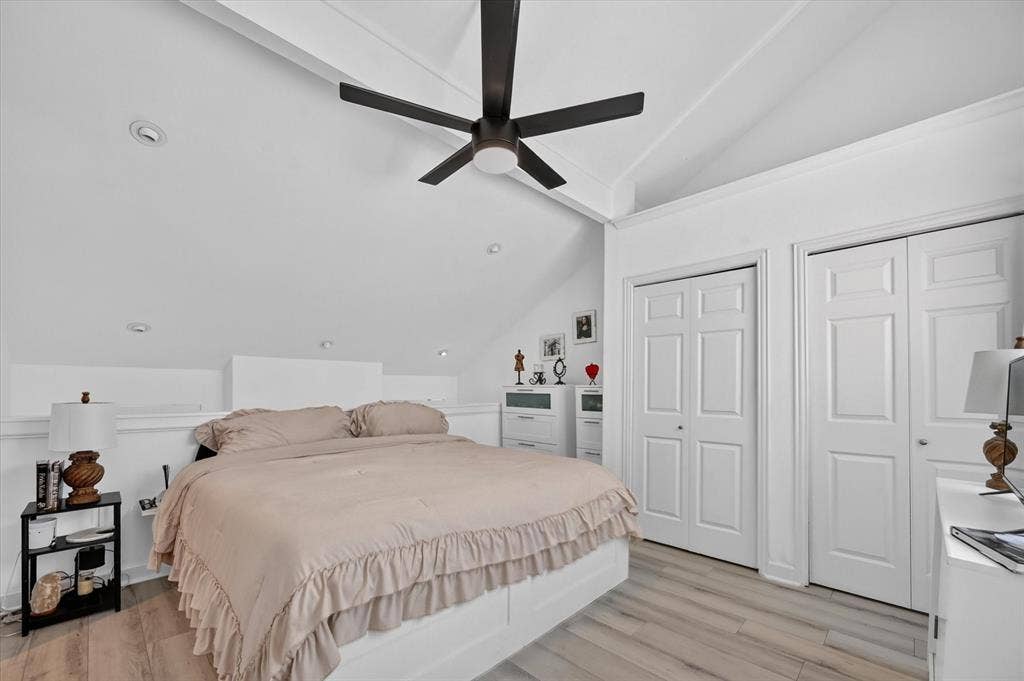 Vaulted ceilings with exposed beams, recessed lighting, wood-finish flooring, and two paneled closet doors