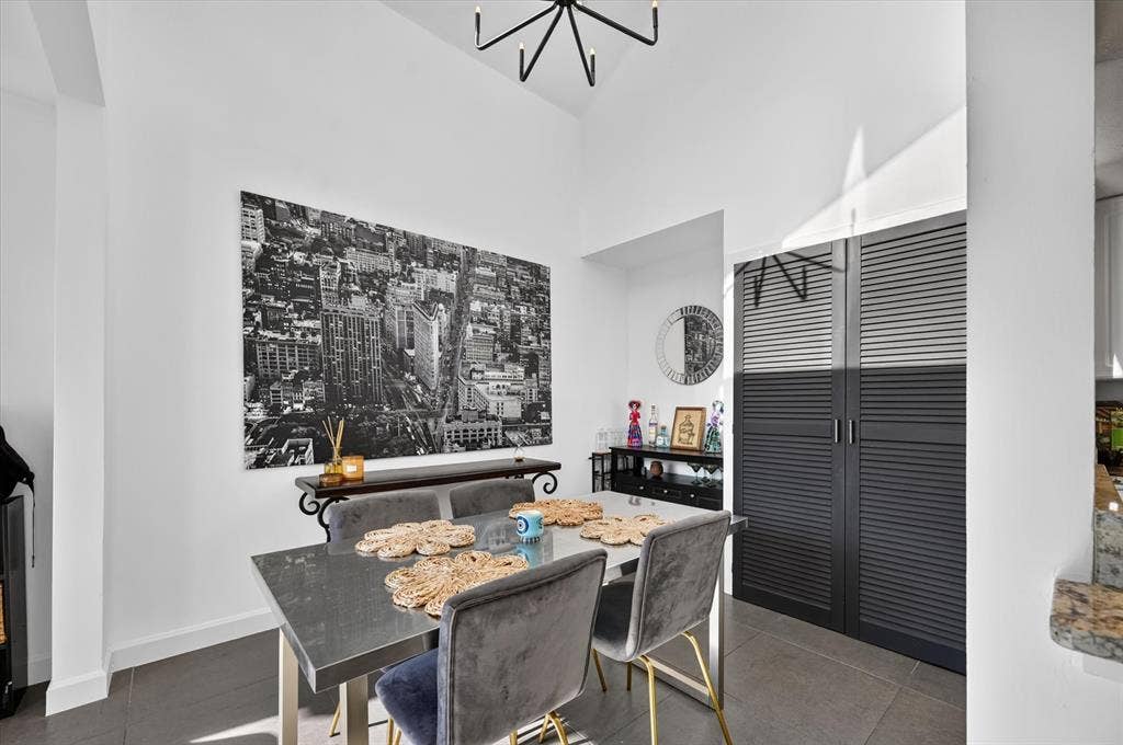 Vaulted ceiling, modern chandelier, dark louvered bifold doors, tile flooring, granite-look countertop
