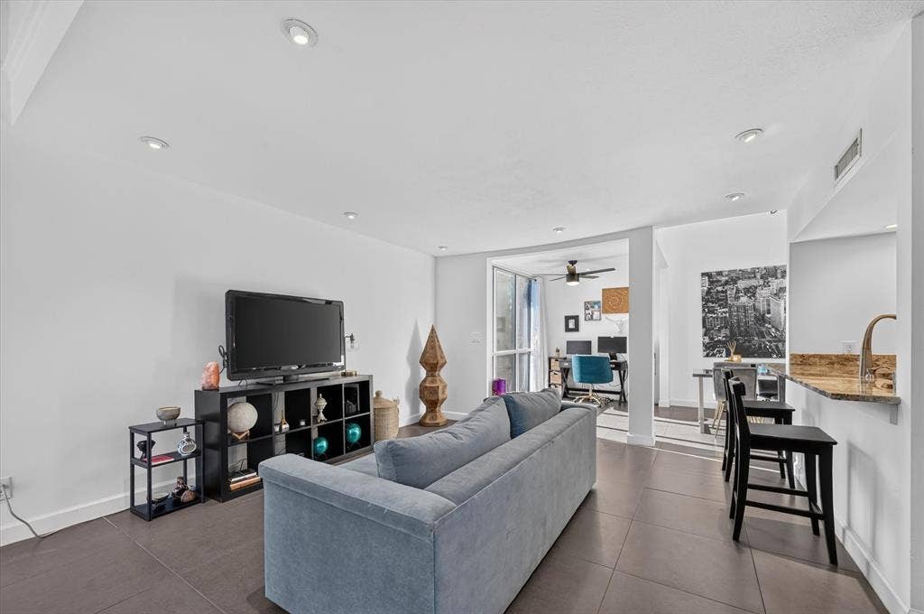 Recessed lighting, tile flooring, and a breakfast bar with a stone-finish countertop