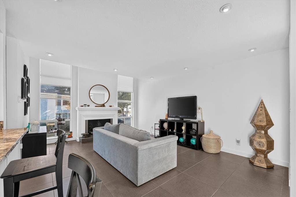 Recessed lighting illuminates the white walls and dark tile flooring