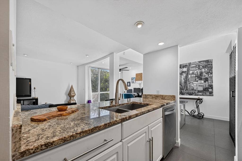 Granite countertops, white cabinetry, dual basin stainless steel sink, and stainless steel dishwasher