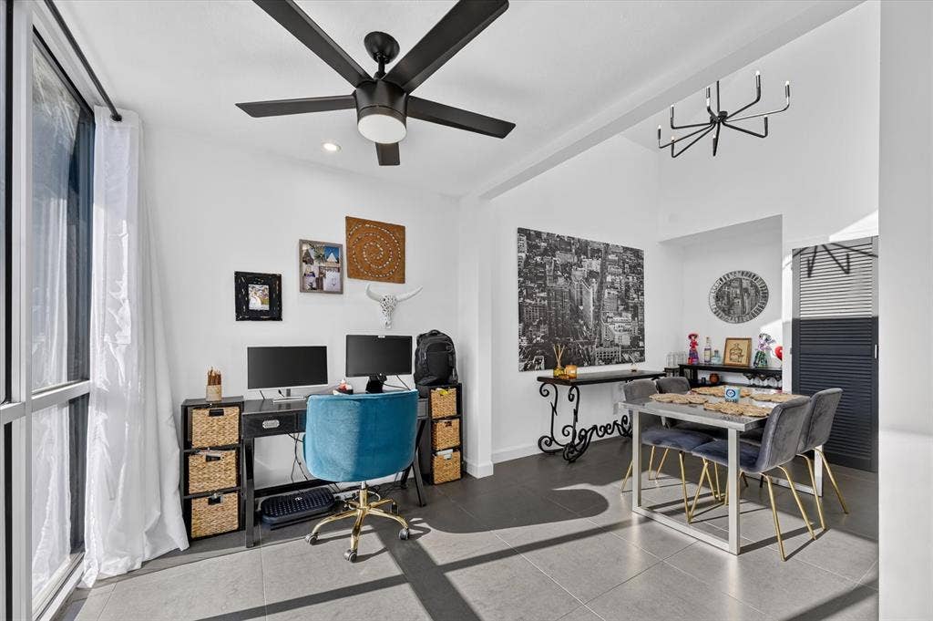 High ceilings with a black ceiling fan, large windows, and gray tile flooring