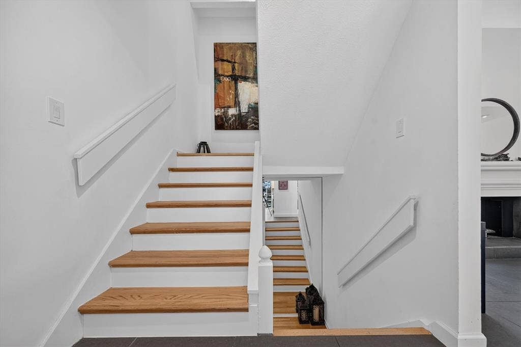 Staircase featuring wood-finish treads and white risers, framed by white walls
