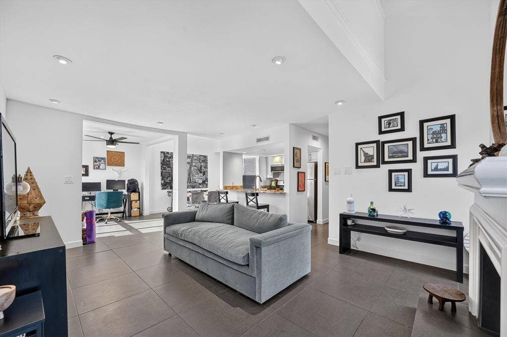 Spacious living area featuring large format tile flooring, recessed lighting, and a white mantel