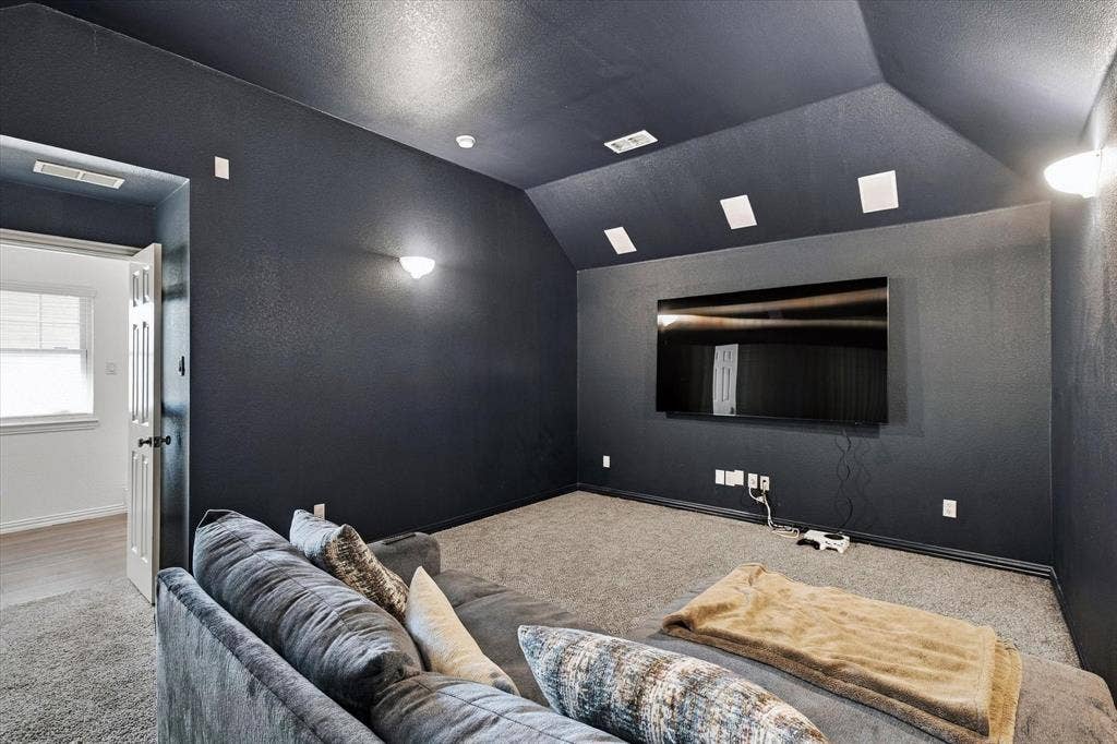 Carpeted flooring, vaulted ceiling, recessed lighting, and wall-mounted sconces