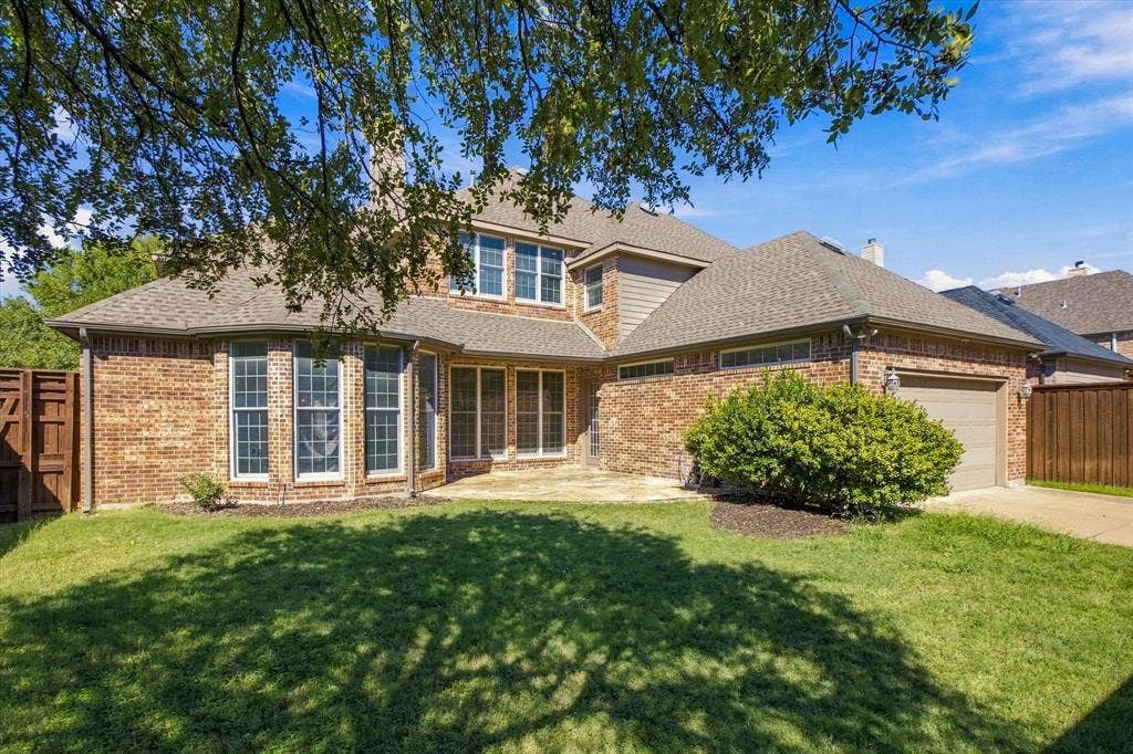 Brick exterior with multiple windows, a stone patio, and an attached garage