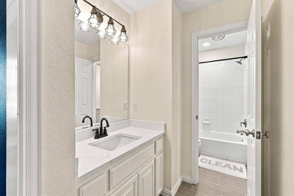 Vanity with white cabinetry, a white countertop, and a black faucet