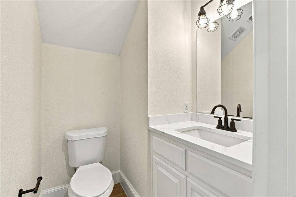 White vanity with a rectangular undermount sink, dark bronze faucet, and a large wall-mounted mirror