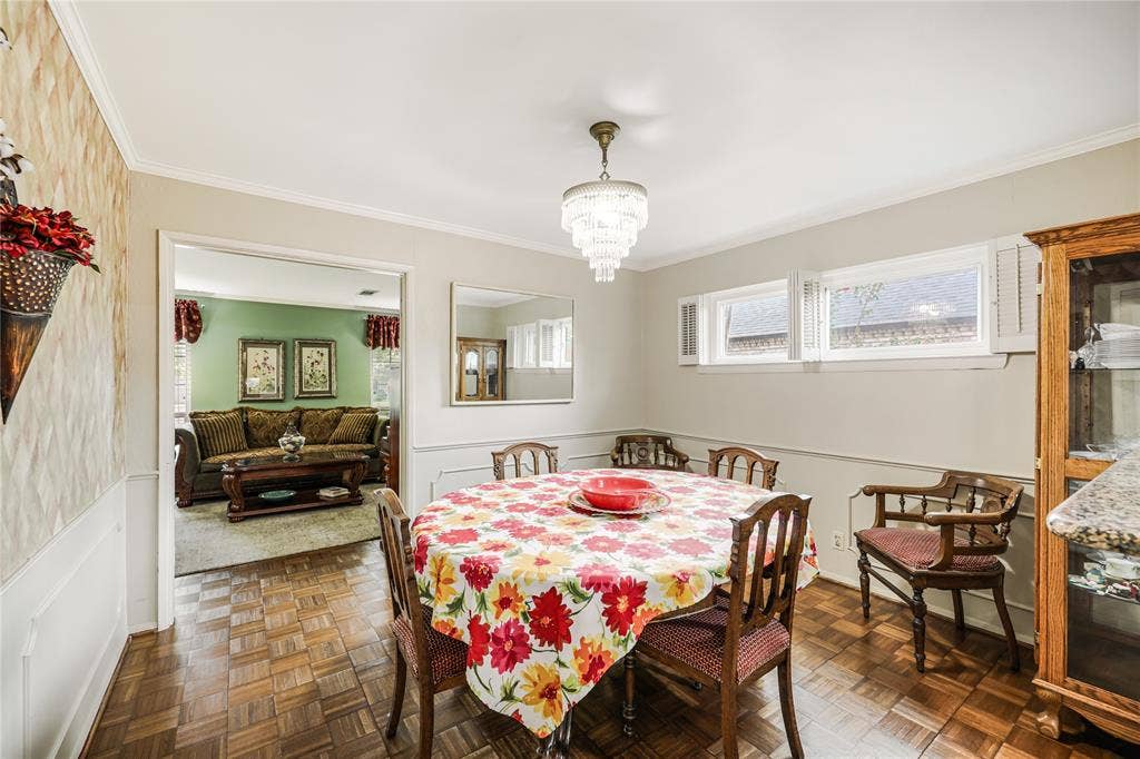 Formal dining room with views into formal front living area has  plantation shutters , picture frame moulding and nNote:  light fixture will be excluded as loved  family heirloom.