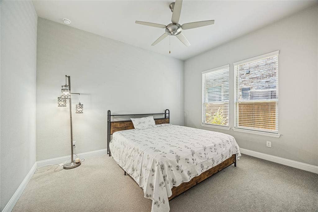 Vaulted ceiling with an attached ceiling fan, two windows with blinds, and light-toned carpeting
