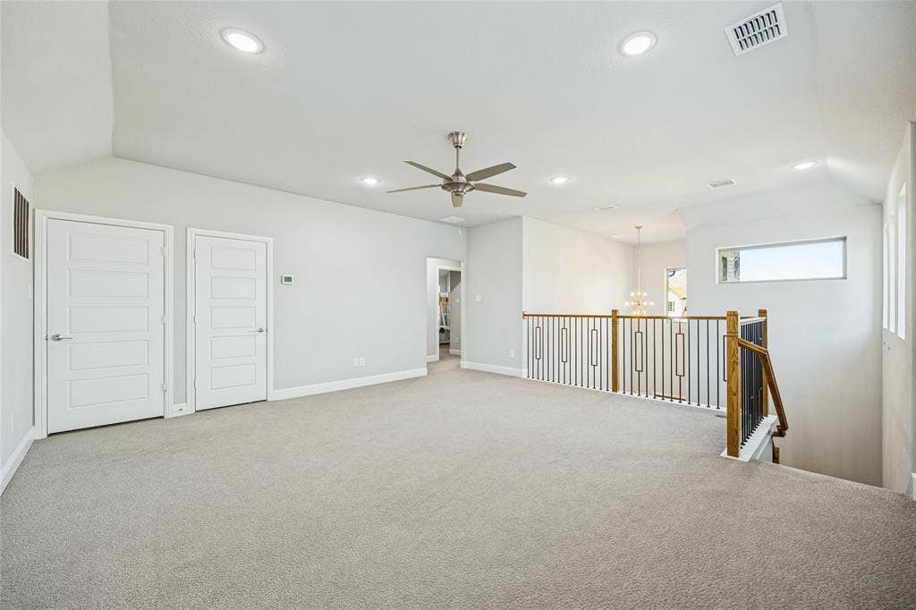 Spacious carpeted room featuring vaulted ceilings, recessed lighting, and a ceiling fan