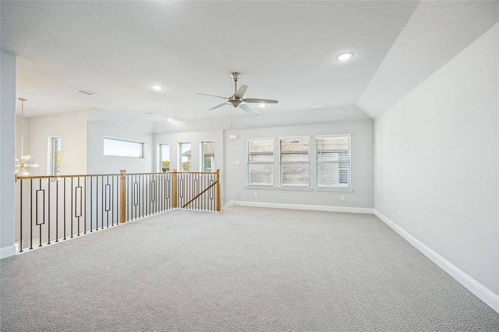 Open loft space with light-toned carpeting and multiple windows