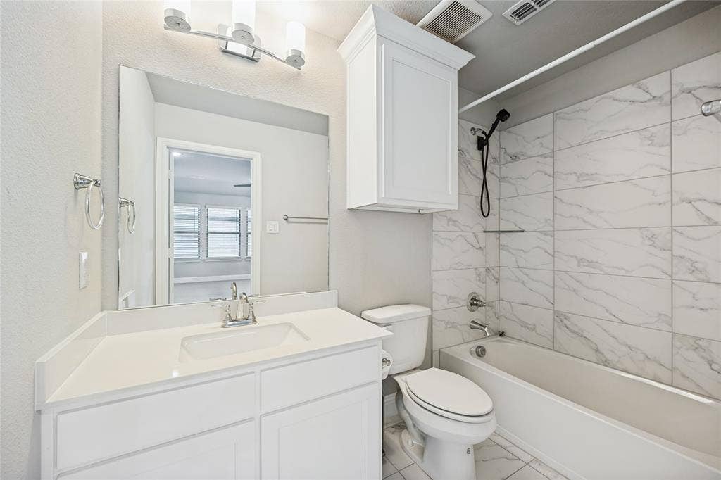 White vanity with a single basin sink, chrome faucet, and quartz-finish countertop