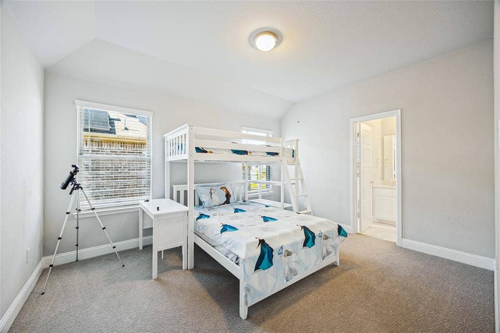 Soft grey wall color, vaulted ceiling, neutral tone carpet, recessed lighting, and a white interior door