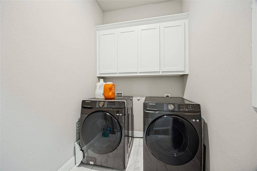 White shaker-style cabinetry with crown molding, light-toned walls, and a durable tile flooring