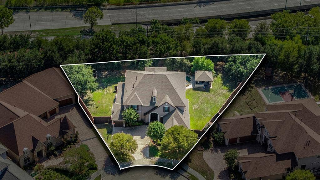 Aerial perspective of a multi-gabled residence featuring a paved driveway, expansive backyard, mature landscaping, and a detached gazebo