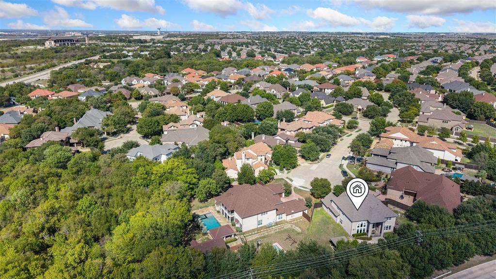 Aerial perspective of a multi-story residence featuring a multi-pitched roofline, stone and brick masonry exterior, and a secluded lot bordering extensive mature trees