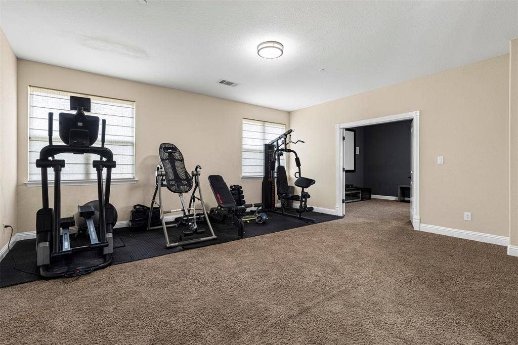 Spacious room featuring carpeting, two windows with integrated blinds, flush-mount ceiling lighting, and double doors opening into a secondary area