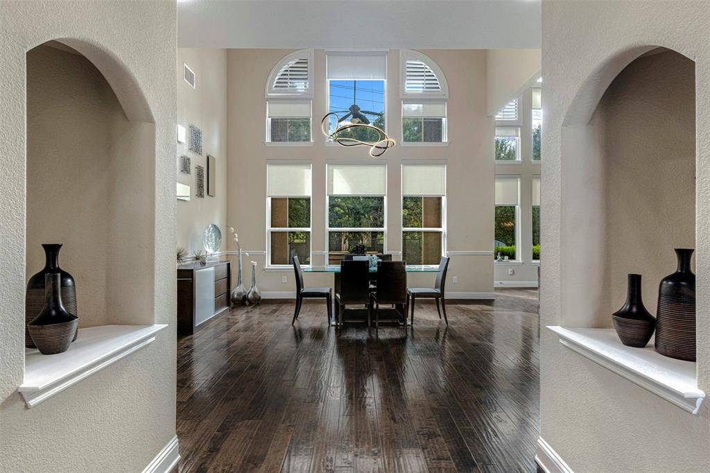 Expansive interior space featuring high ceilings, dark wood-finish flooring, dual built-in arched wall niches, and a multi-pane window configuration with arched top panels