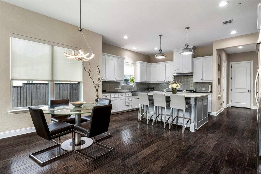 Kitchen featuring wood-finish flooring, white cabinetry, a center island with stone countertop, stainless steel range hood, and recessed lighting