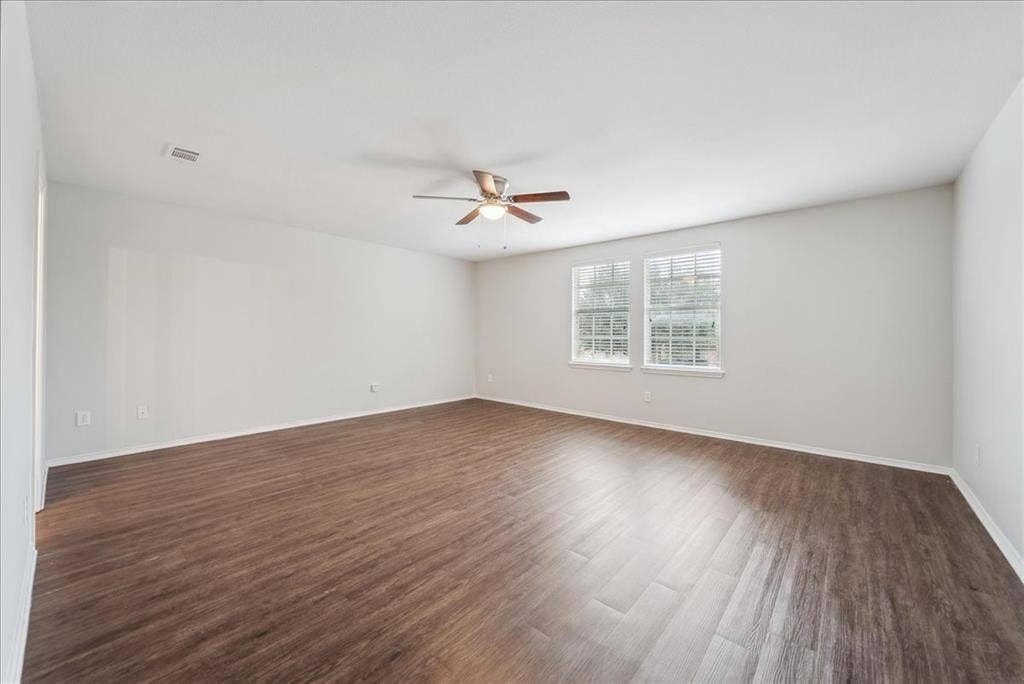 Spacious interior featuring wood-finish flooring, light-colored walls, and a ceiling fan