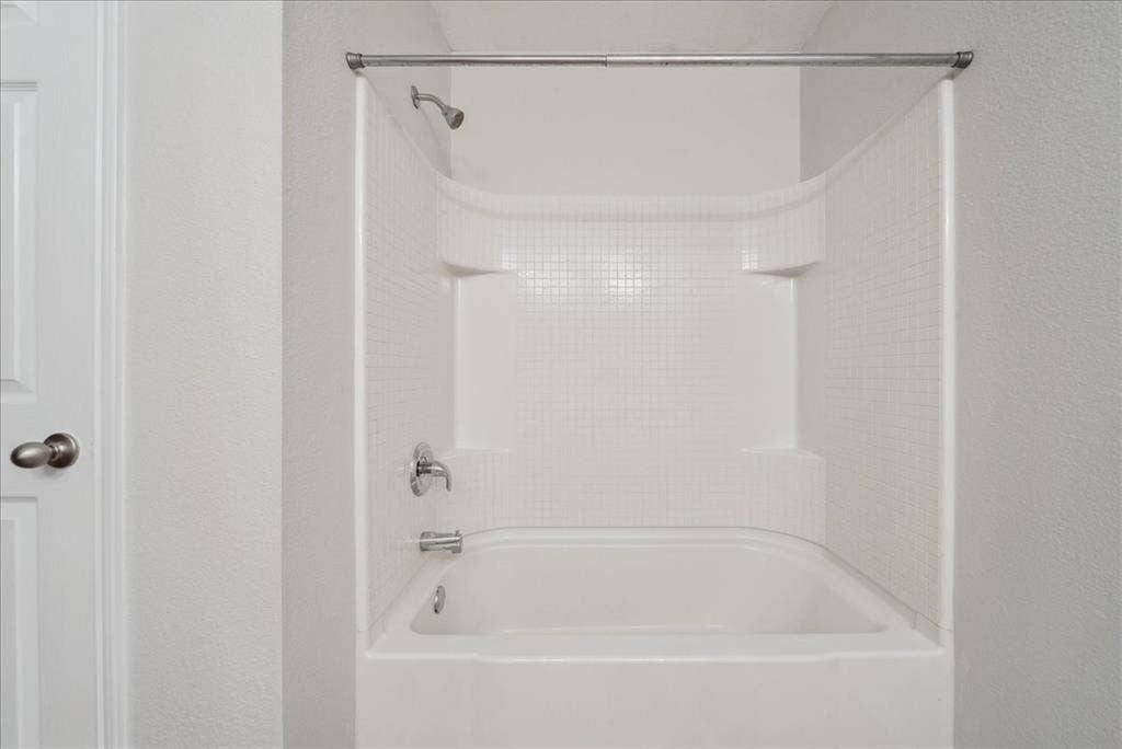 Bathtub with integrated shelving, chrome fixtures, and a shower curtain rod