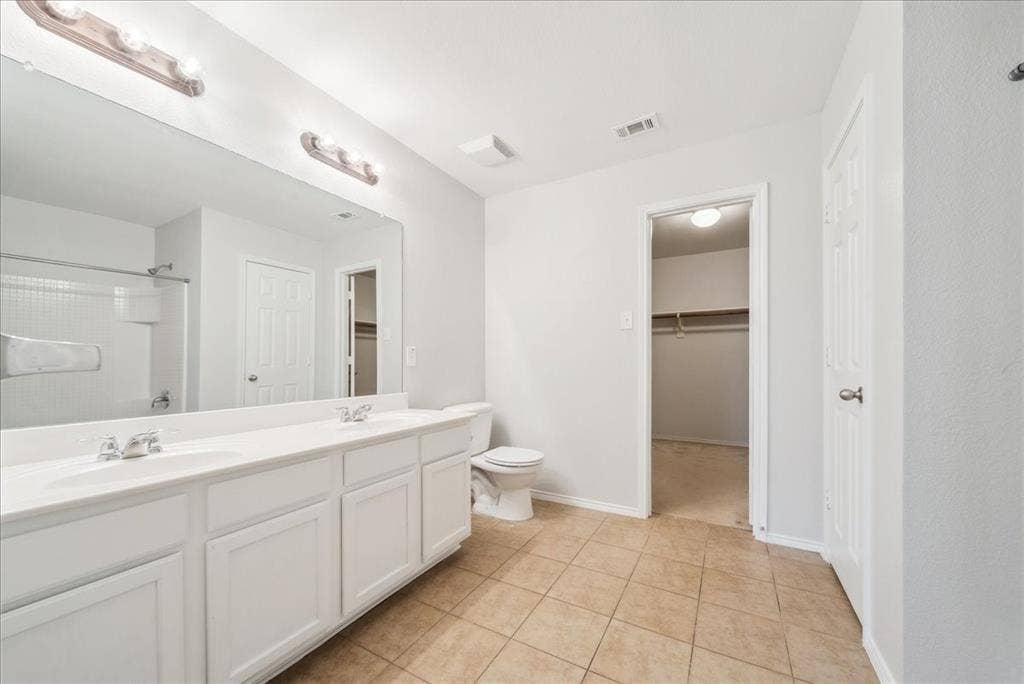 Dual vanity with undermount sinks, tile flooring, and a shower-tub combination