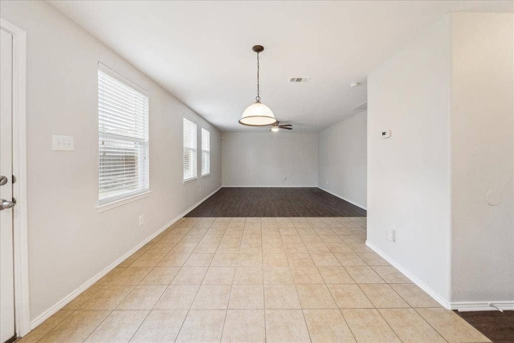 Light-toned tile flooring, white walls, and multiple windows with blinds