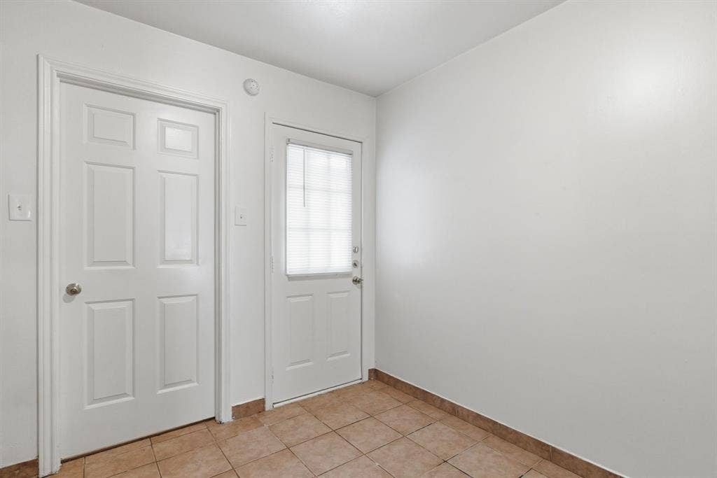 Neutral wall paint, tiled flooring, and multiple panel doors