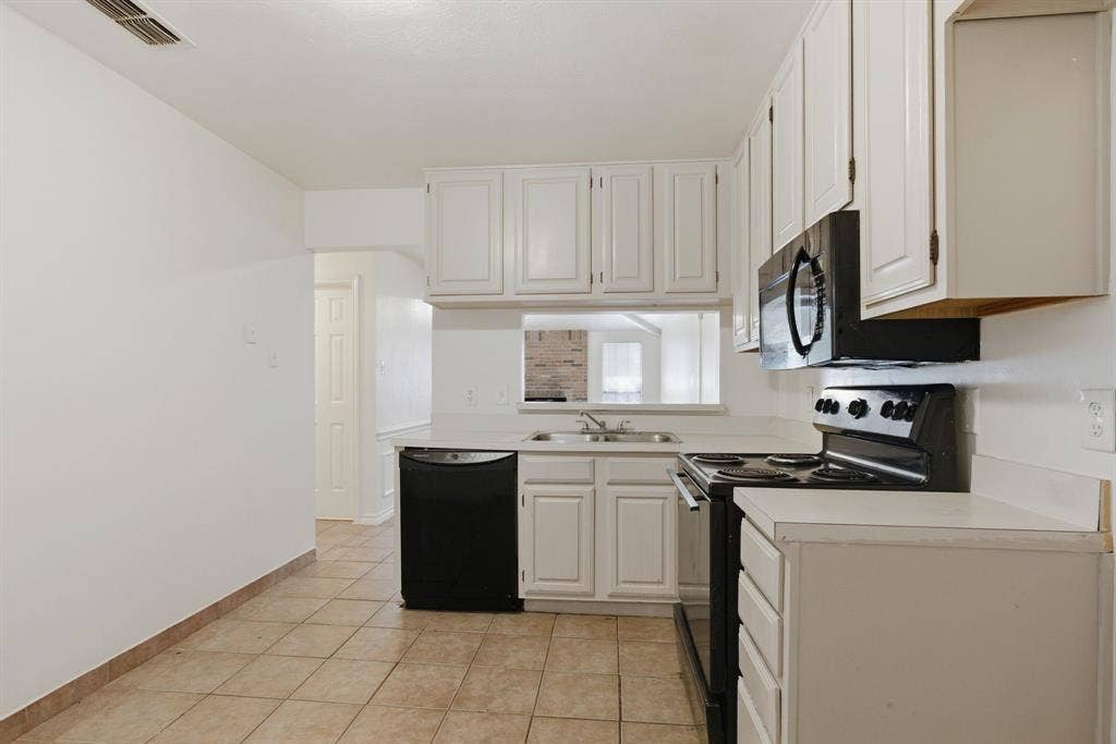 White cabinetry with black hardware, white countertops, stainless steel double basin sink, black built-in microwave, and black range